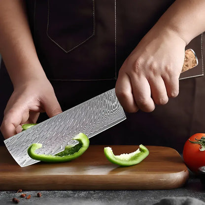 Nakiri Essence de Tsubaki en action tranchant un concombre vert avec efficacité sur planche de cuisine.