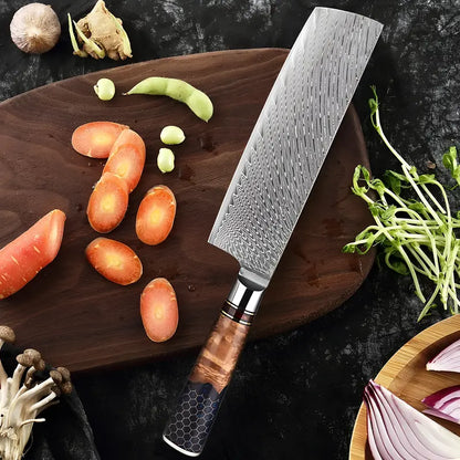Couteau Nakiri Vent de Kaede présenté sur planche ronde avec légumes découpés et herbes fraîches.