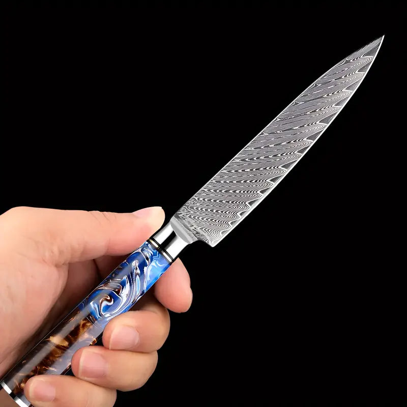 Océan de Yami tenu en main, montrant sa lame damassée et son manche au design inspiré des profondeurs marines.