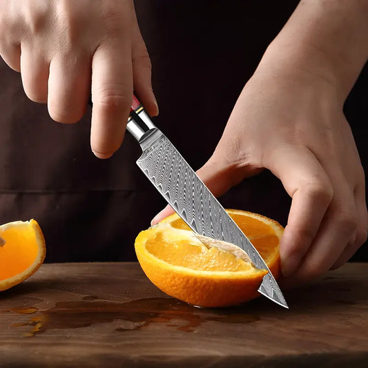 Le Petty Flamme de Kyoto en pleine découpe précise d’une orange illustrant la finesse de sa lame damassée.