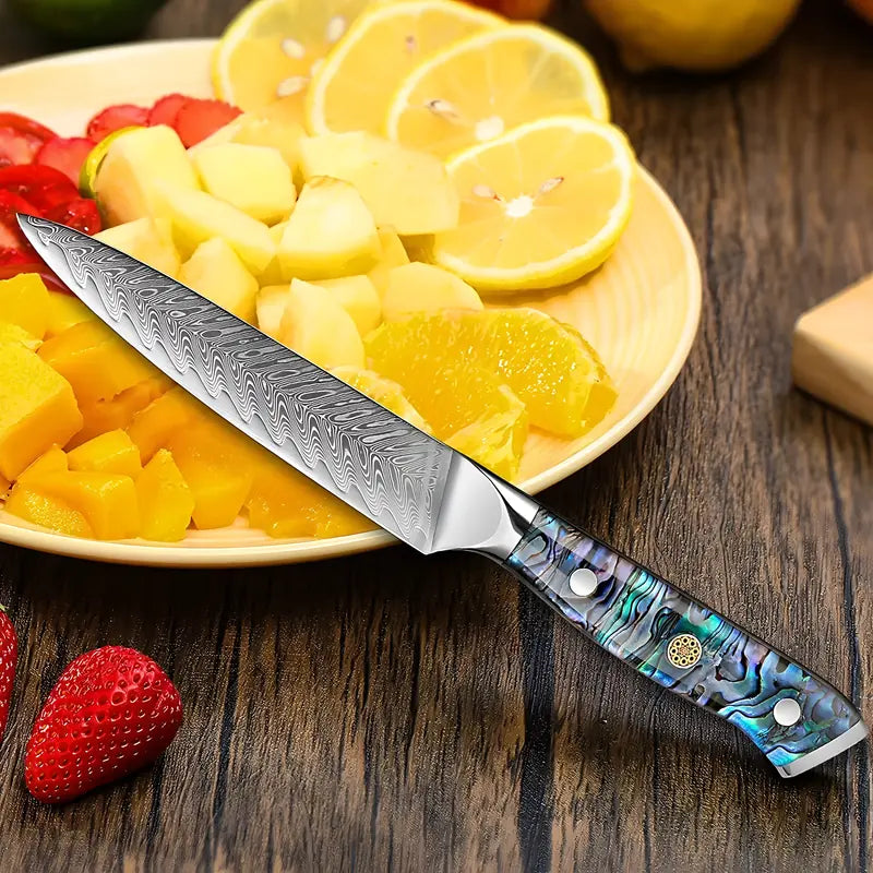 Couteau d’office Lame Céleste sur table en bois, à côté d’oranges, fraises et ananas fraîchement découpés.