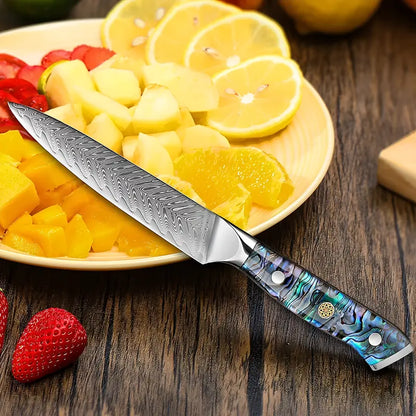 Couteau d’office Lame Céleste sur table en bois, à côté d’oranges, fraises et ananas fraîchement découpés.