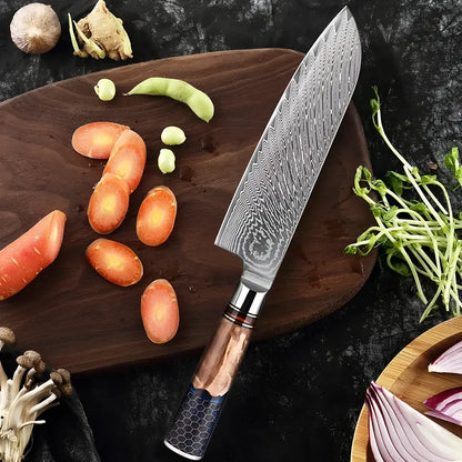 Couteau Santoku 67 couches posé à côté de légumes variés, sur une planche arrrondie en bois foncé.