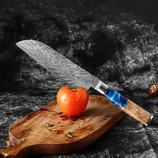 Couteau Santoku damassé 67 couches posé à côté d’une tomate fraîche sur une planche rustique.