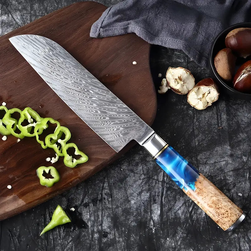 Couteau Santoku en damas 67 couches, manche bleu et bois clair entouré de légumes et chataignes découpés.