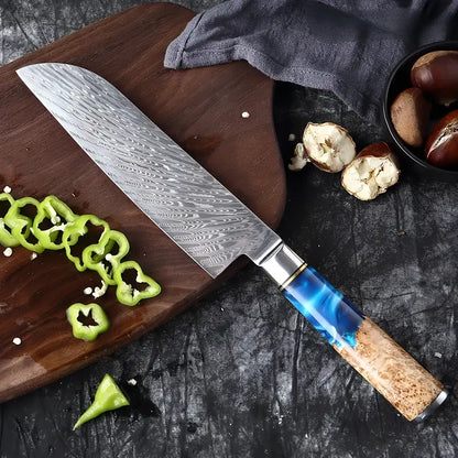 Couteau Santoku en damas 67 couches, manche bleu et bois clair entouré de légumes et chataignes découpés.