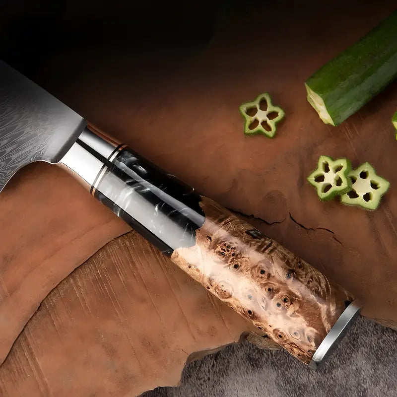 Zoom sur le manche en bois stabilisé et la lame damassée du couteau Santoku posé sur une planche.
