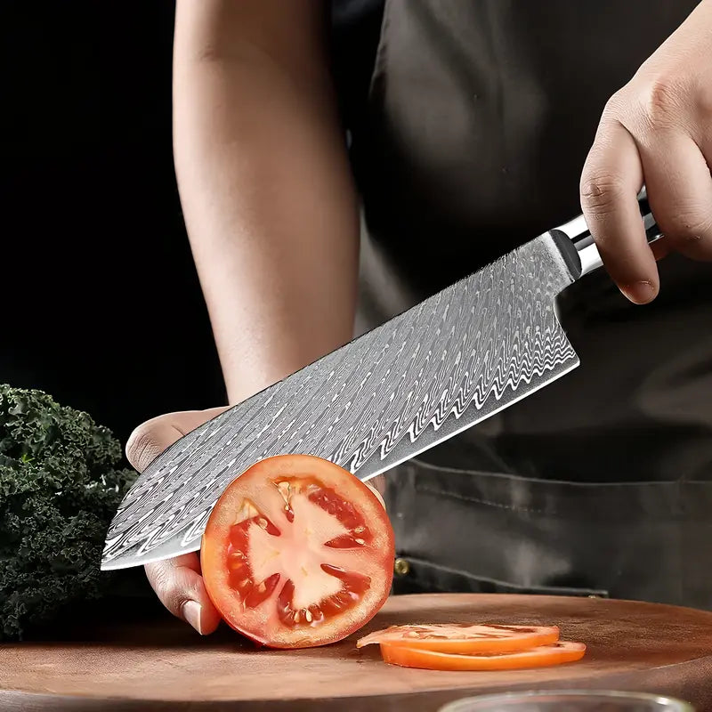 Couteau Santoku en acier damas 67 couches en train de trancher une tomate mûre sur une planche.