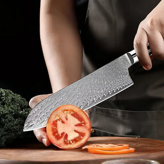 Couteau Santoku en acier damas 67 couches en train de trancher une tomate mûre sur une planche.