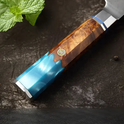 Gros plan sur le manche en bois stabilisé bleu du couteau Santoku en acier damas 67 couches.