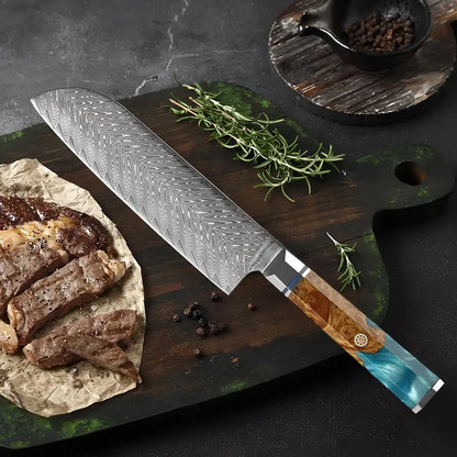 Couteau Santoku en acier damas 67 couches posé à côté d’une pièce de viande grillée et de fines herbes.