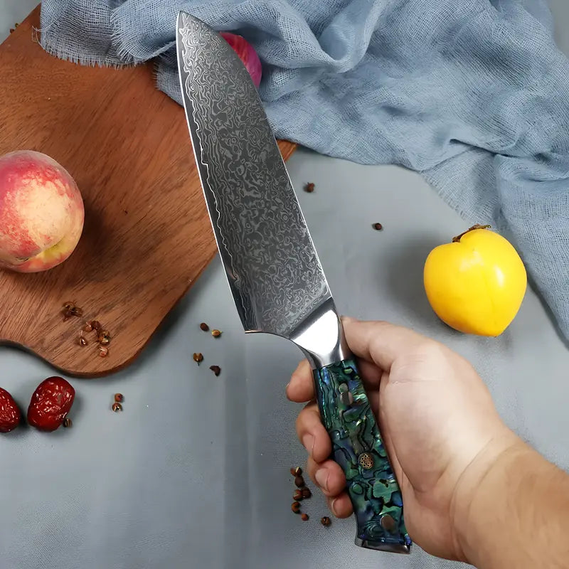 Gros plan sur le Santoku Lame Céleste, dans une main à côté d’un citron et d'une planche.