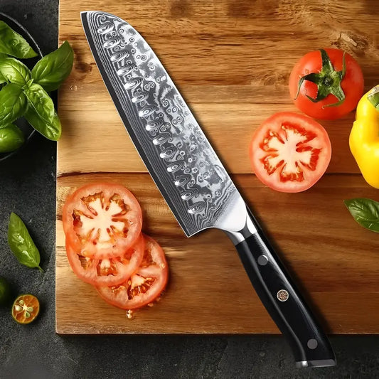 Tranchage de tomates avec un couteau Santoku damas sur planche de bois.