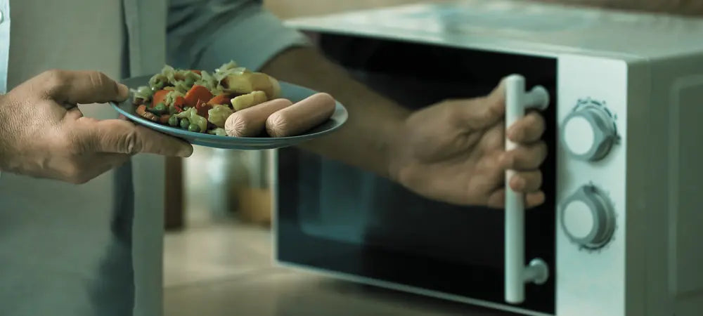Assiette devant un micro onde, symbolisant le manque de temps pour cuisiner des plats fait maison.